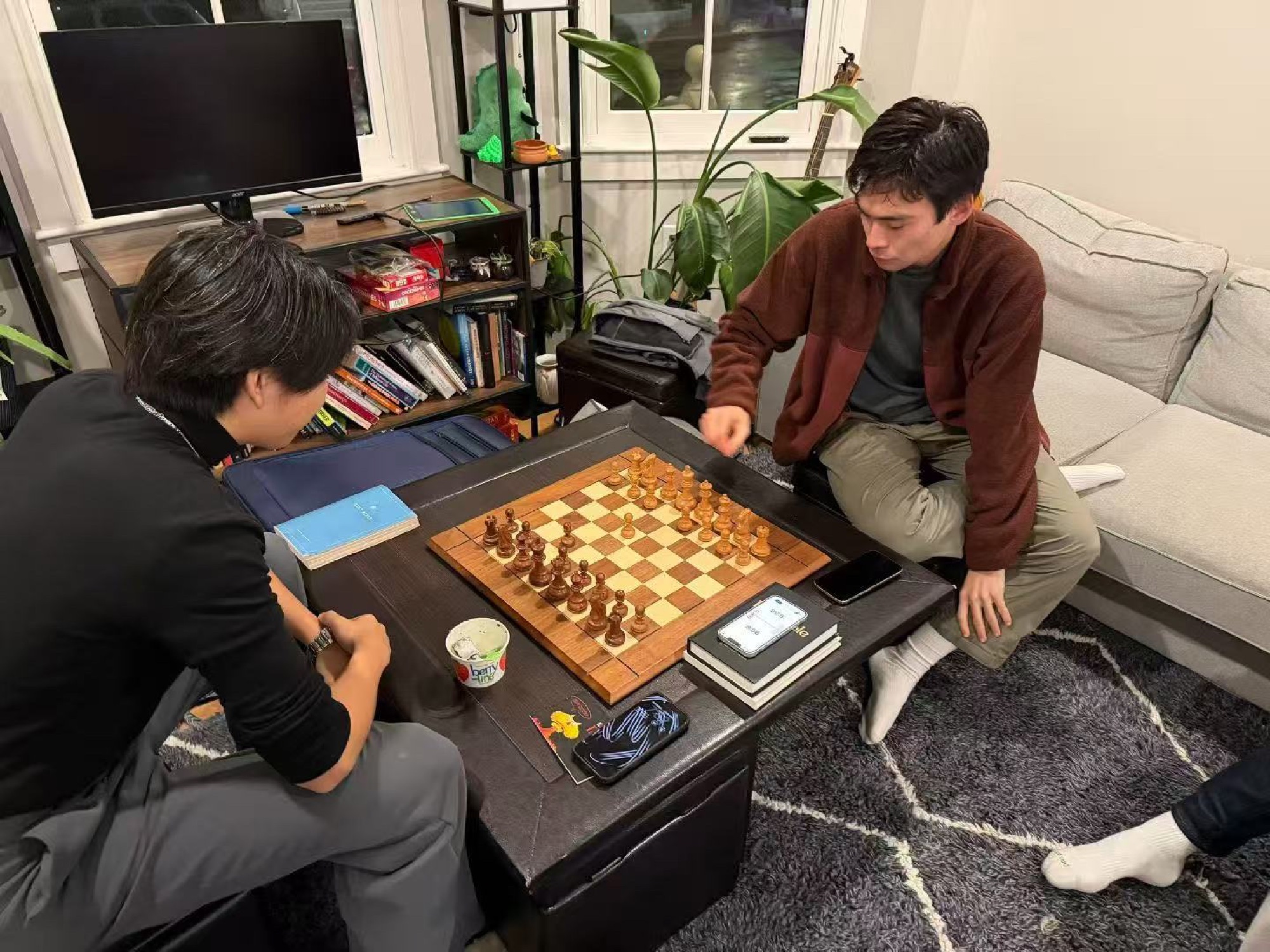 Two people playing chess in a living room