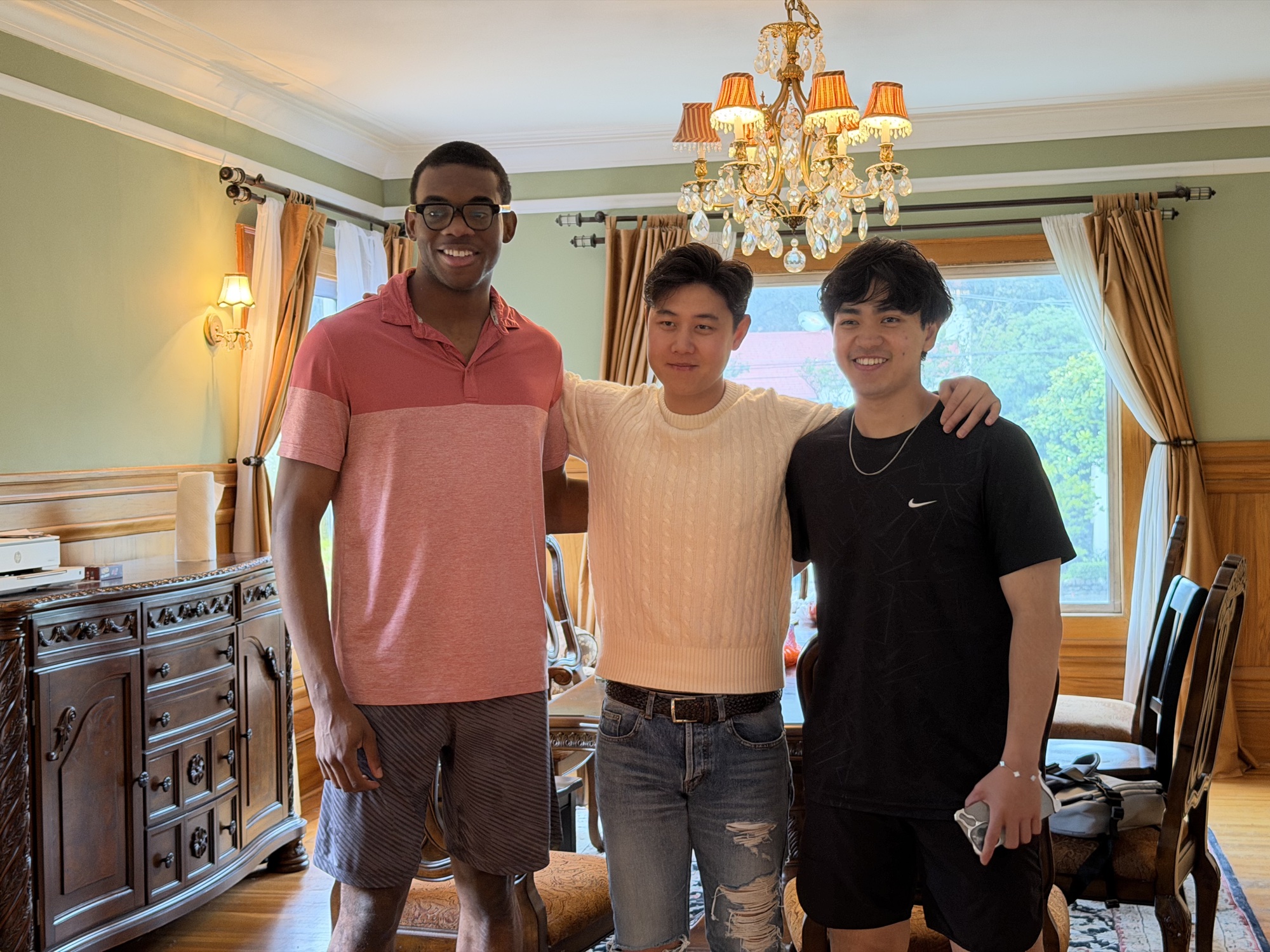 Three friends standing together in a warmly lit room